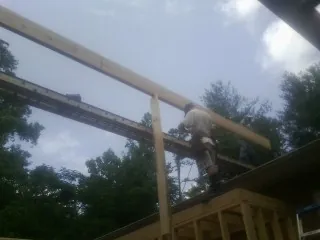 Carpenter setting a ridge beam over a new addition frame — Ice Dam Removal by Roofing Brothers in Cave Spring