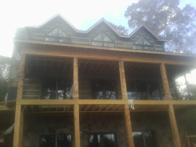 Dormers and porch framing on a large log home under construction — Roof Coating work by our crew in Cave Spring