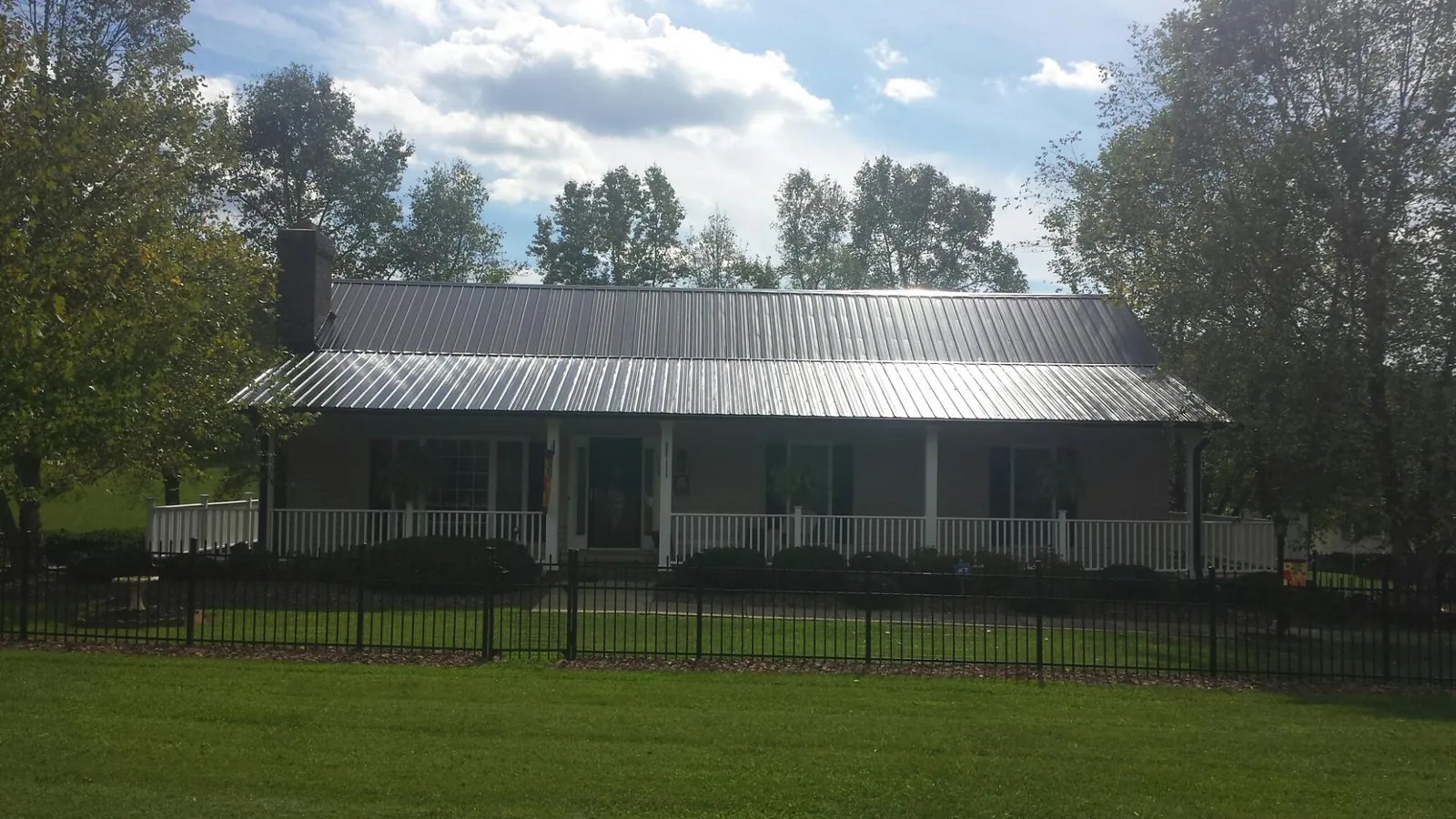 Gray metal roof on a brick ranch with a full width front porch — Gutter Guard Installation work by our crew in Cave Spring