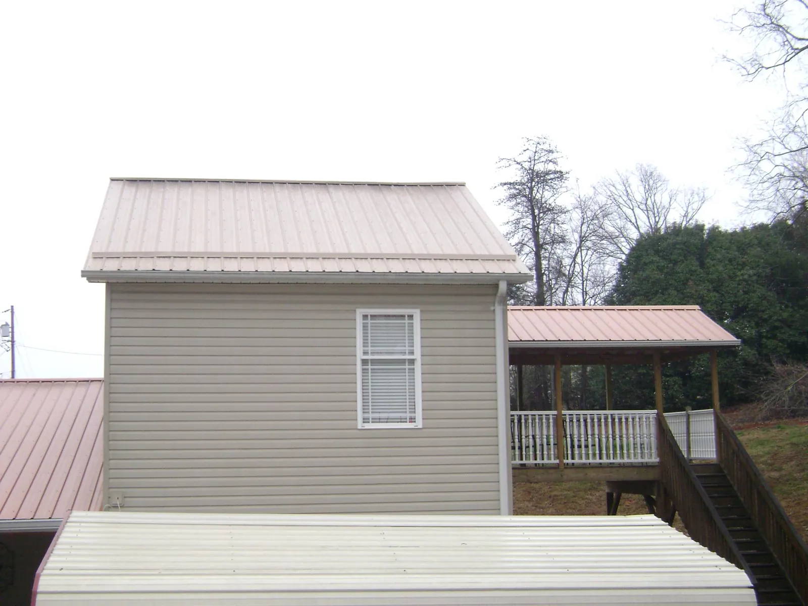 Tan metal roofs on a two story addition and attached porch, from a Roof Replacement job in Cave Spring