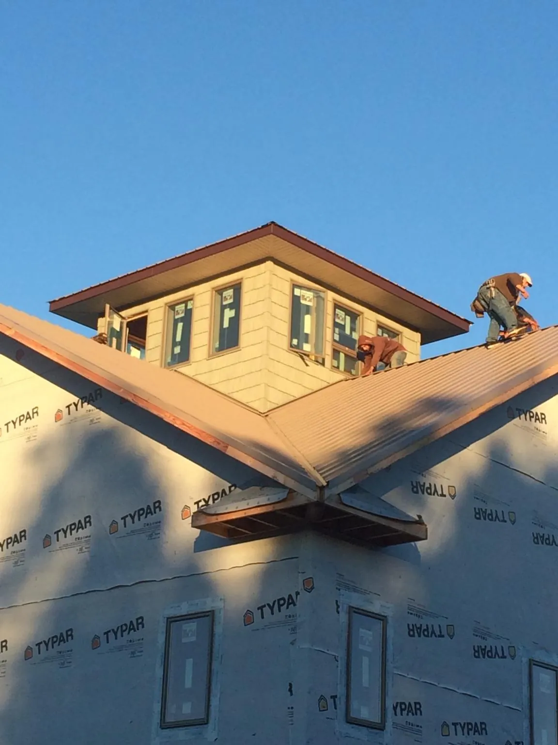Roofers working around a rooftop cupola on a new metal roof at sunset — Roof Waterproofing in Cave Spring by Roofing Brothers